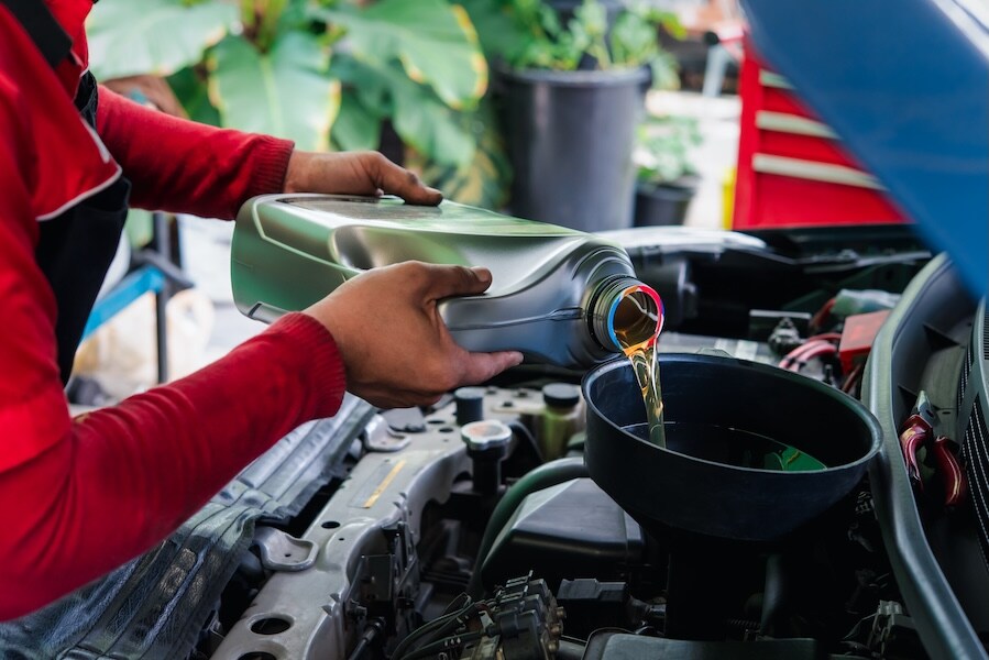 A technician pouring oil into a vehicle's engine A technician pouring oil into a vehicle's engine