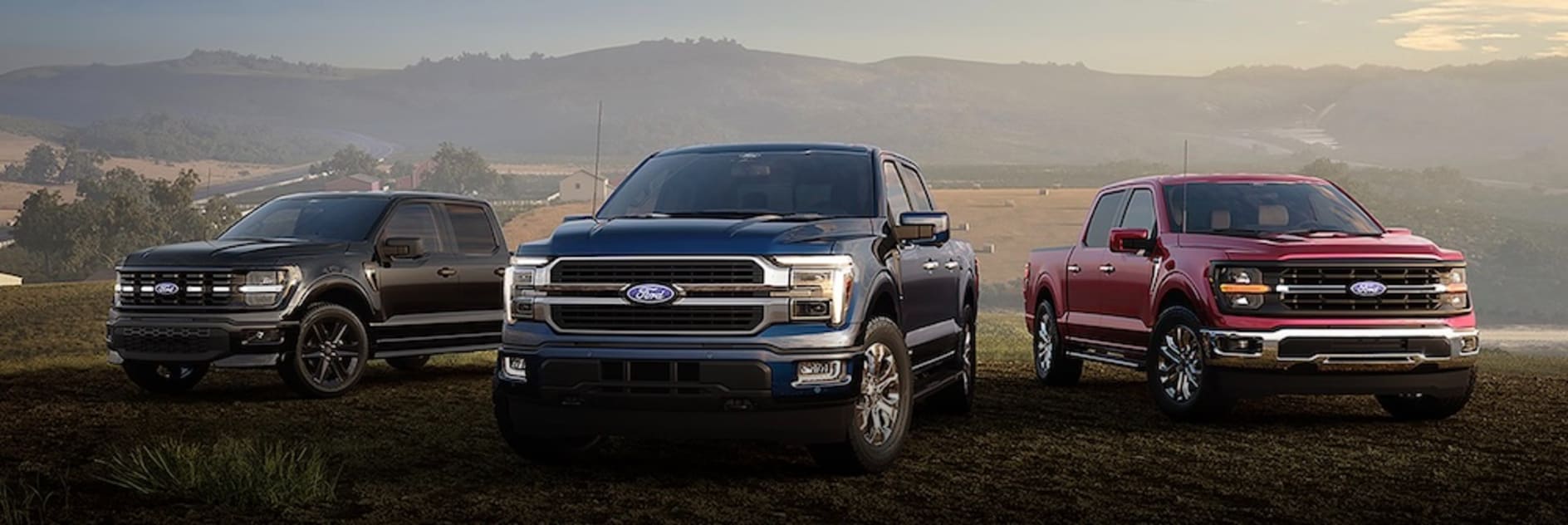Three Ford pickup trucks, one black, one dark blue, and one red, parked in a field with mountains in the background