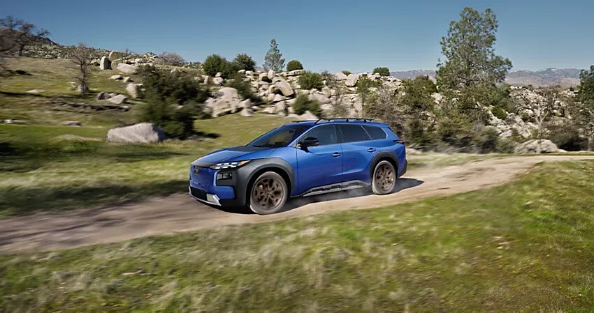 Blue Subaru Trailseeker electric SUV driving quickly along a dirt road