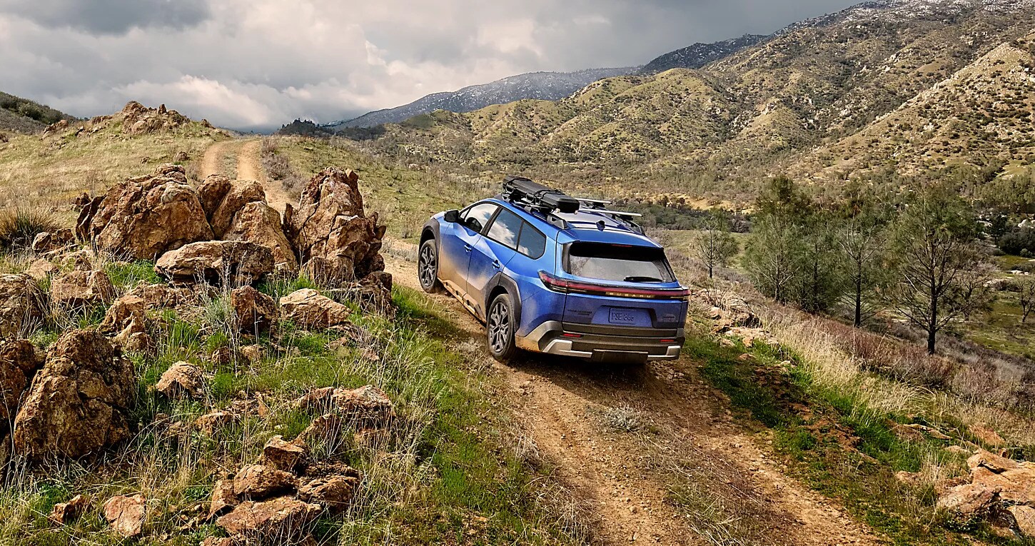 Blue Subaru Trailseeker electric SUV driving on a rocky mountain trail