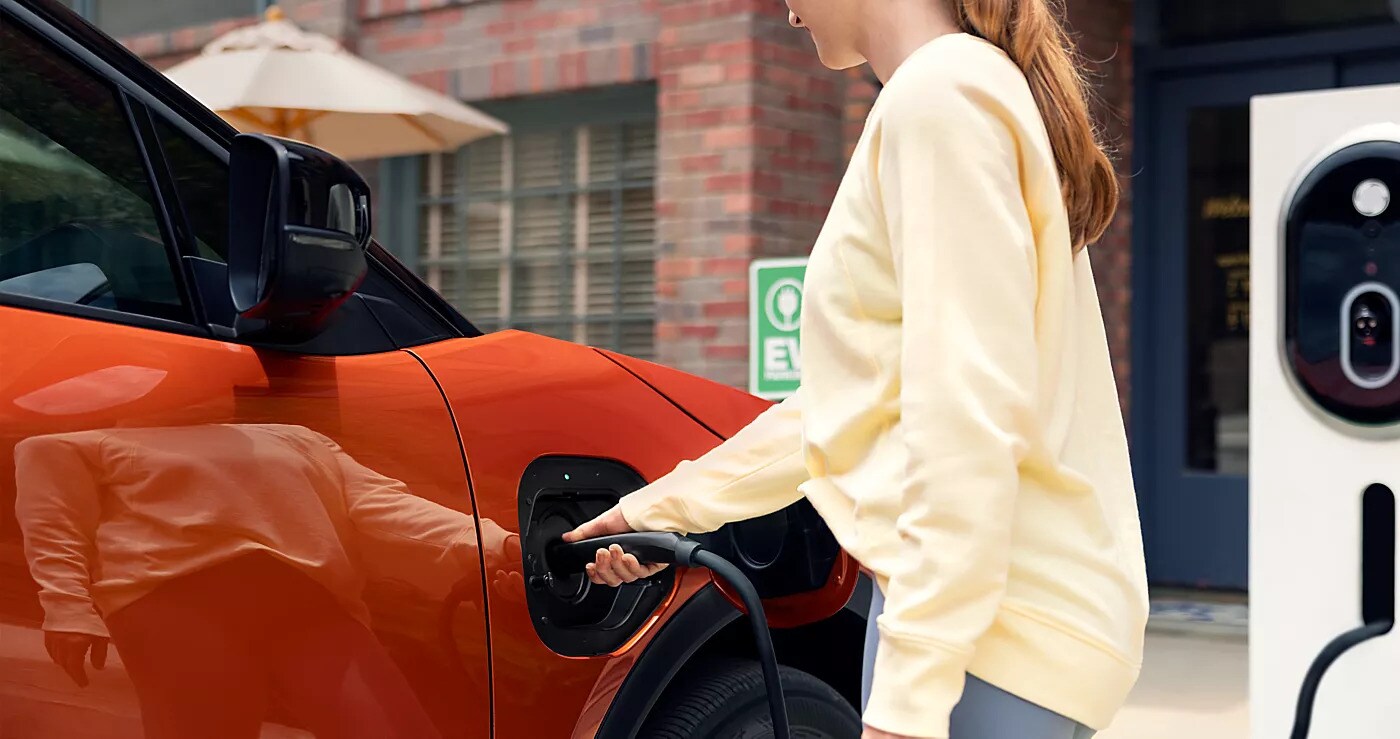 Orange Subaru electric vehicle connected to a public charging station
