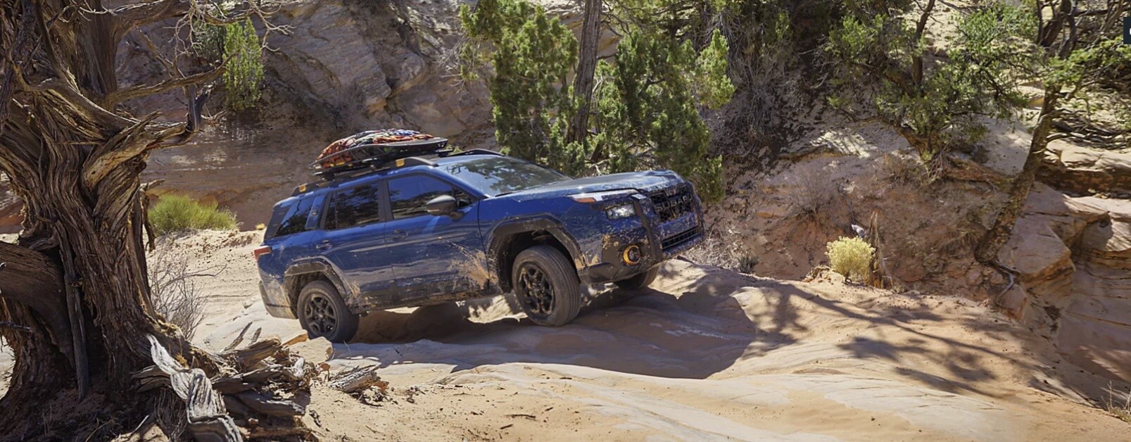 Blue 2026 Subaru Outback driving over rocky terrain