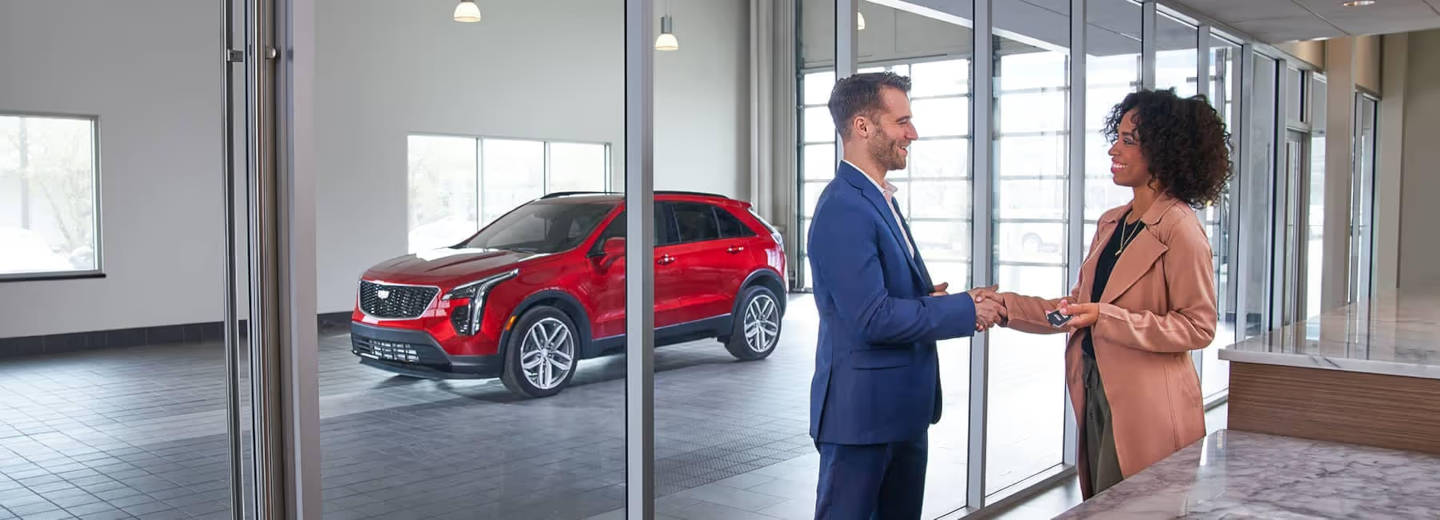 Women taking the keys of a cadillac from a salesman