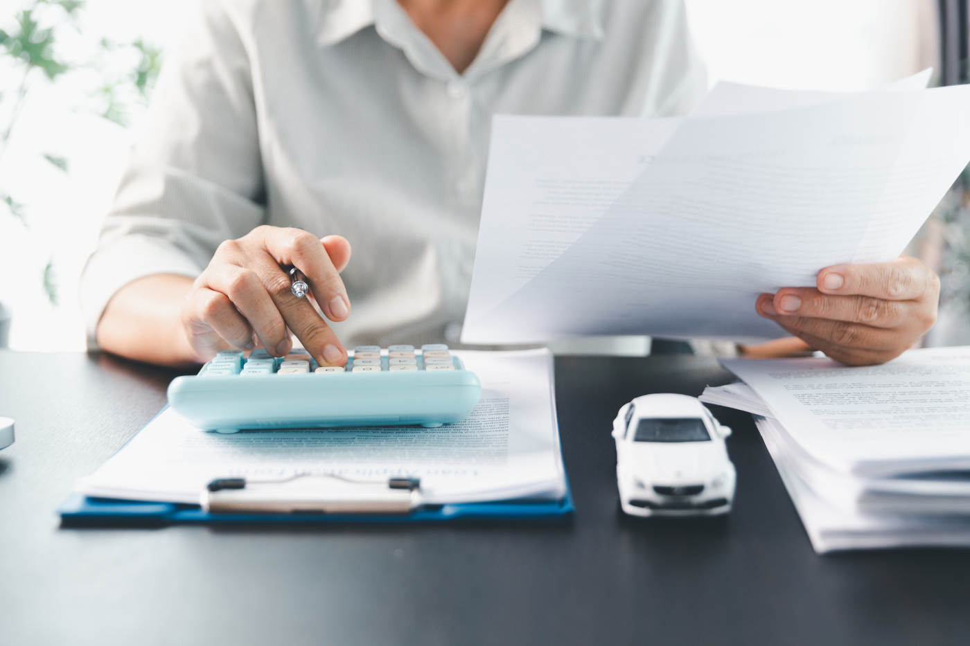 Car dealer businesswoman signing car insurance document or lease paper.