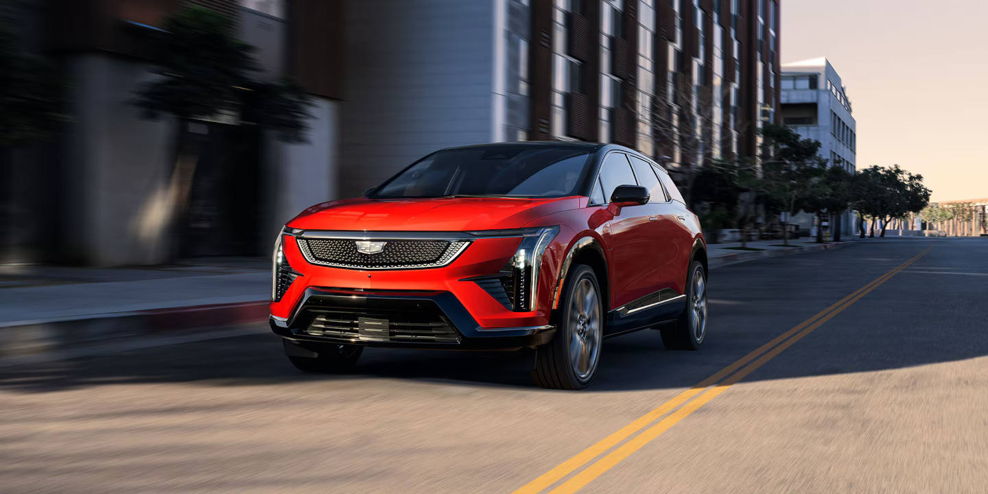 2026 Cadillac OPTIQ driving past modern apartment buildings