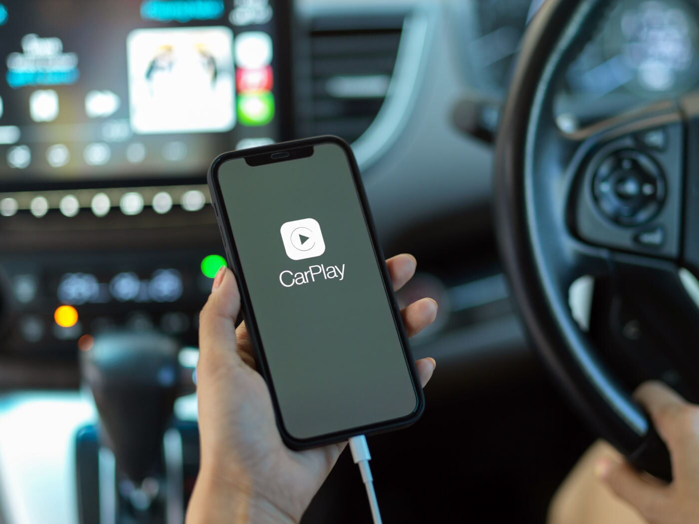 female hand holding smartphone with CarPlay application
