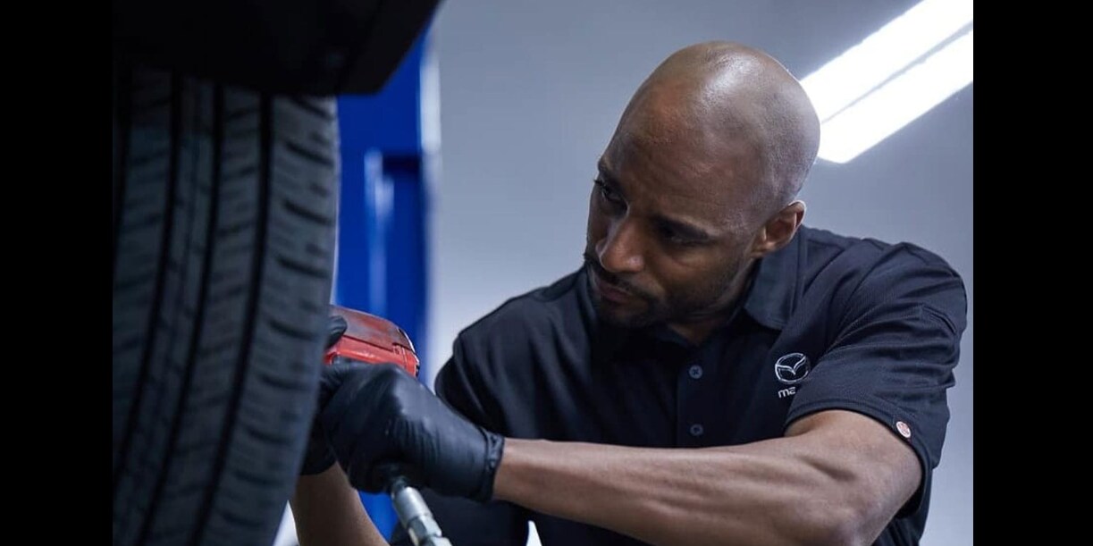 Mazda%20service%20technician Mazda service technician inspecting a tire and wheel in the shop