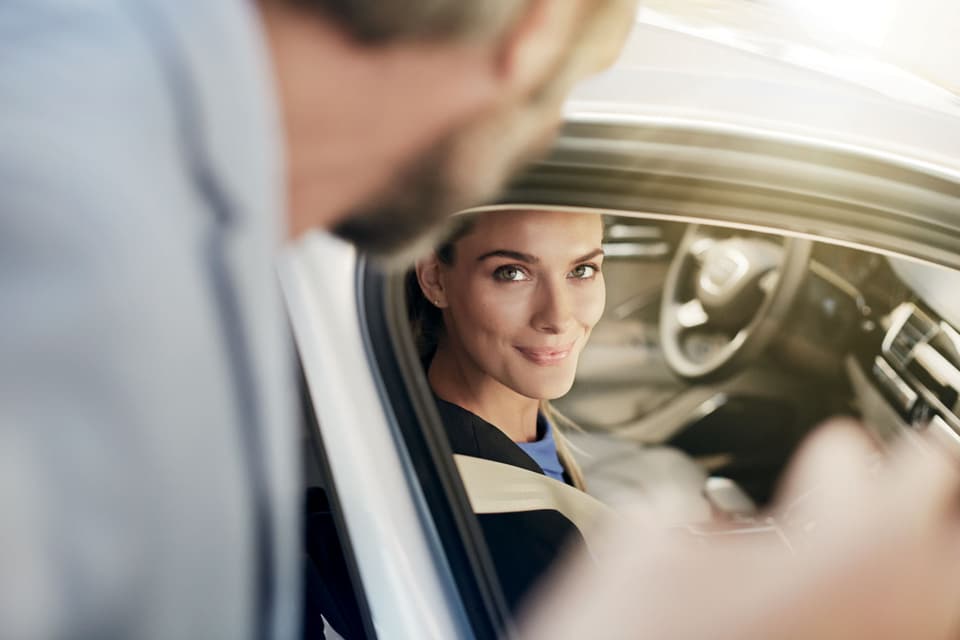 Audi-Lifestyle smiling white woman in driver's seat looks out window at man.jpeg