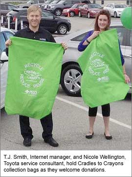 T.J. Smith, Internet manager, and Nicole Wellington, Toyota
service consultant, hold Cradles to Crayons collection bags as they
welcome donations.