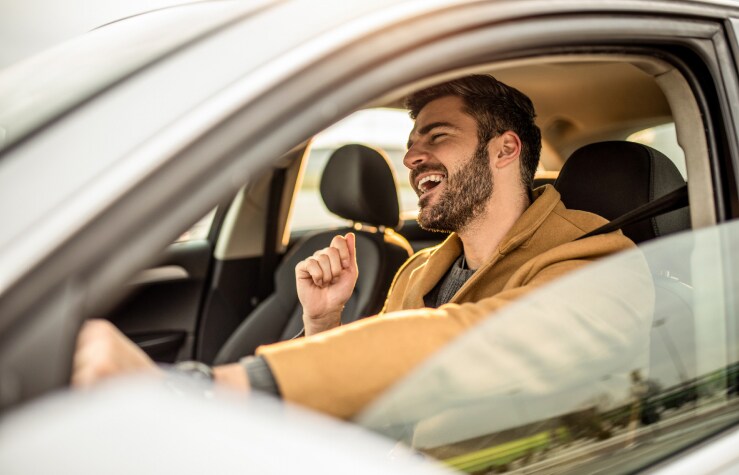 Man smiling and singing while driving his new car.