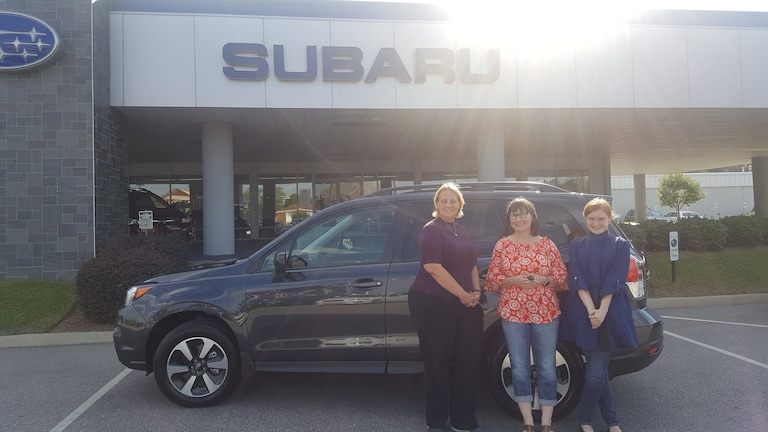 Katherine, daughter Ivy, and Sales Advisor Kristen in front of Katherines 4th Subie- a 2017 Forester.jpg