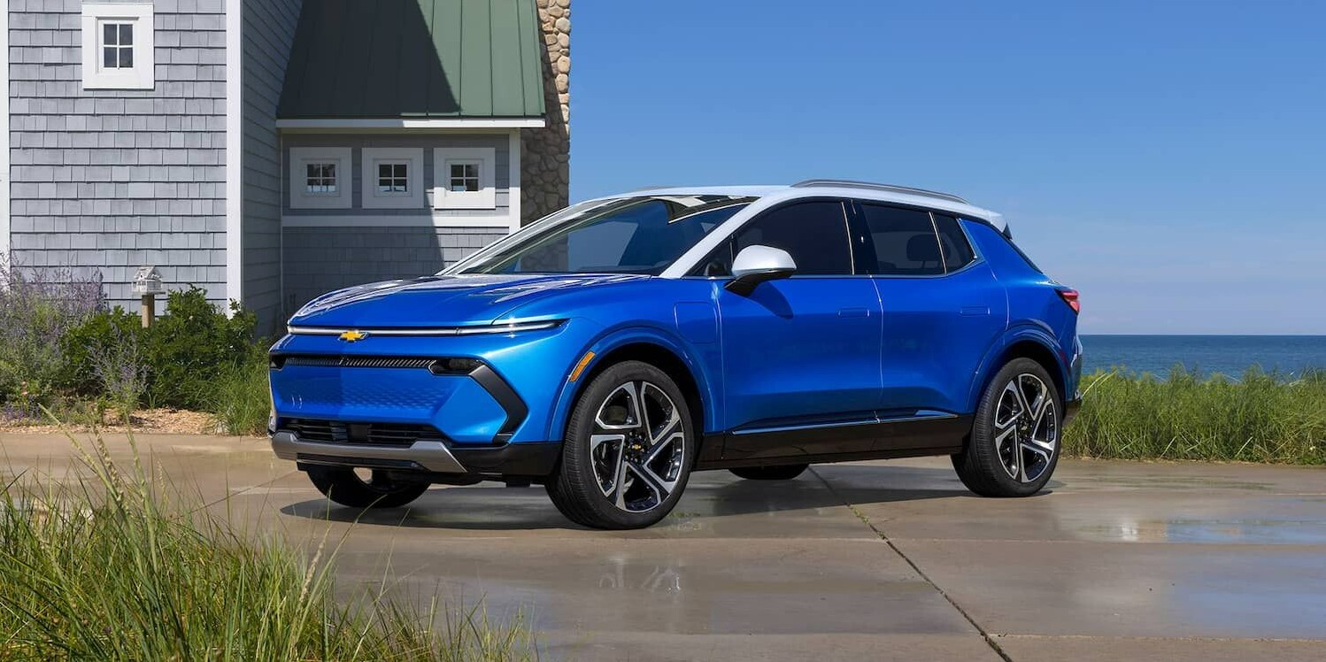 2023-Chevy-Equinox EV-2.PNG A cobalt blue 2023 Chevy Equinox sits parked in front of a shingle house on the coast.