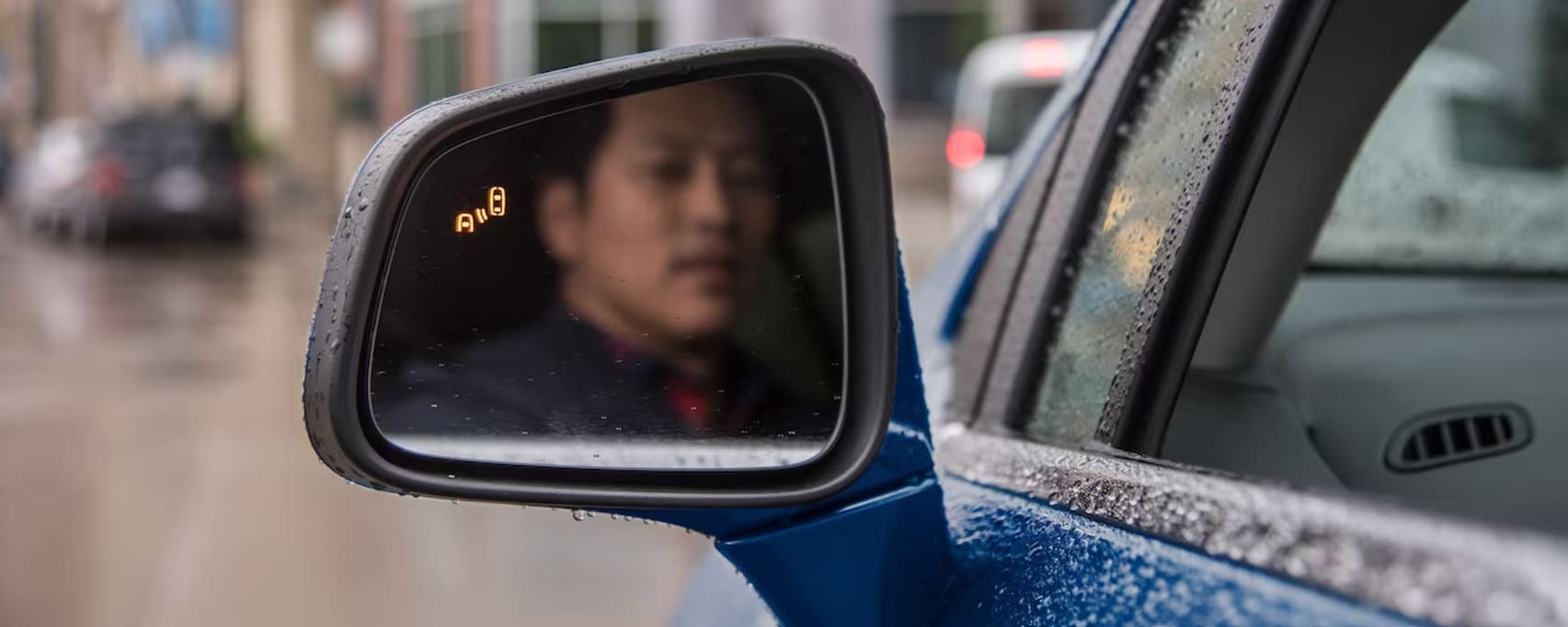 Chevy Safety 2023-10-16 112037.png A man looking through the driver mirror with a blind spot warring on.