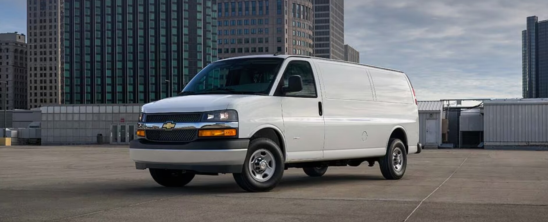 2023-chevy-express-2.PNG A white 2023 Chevy Express Van sits parked in a city parking lot