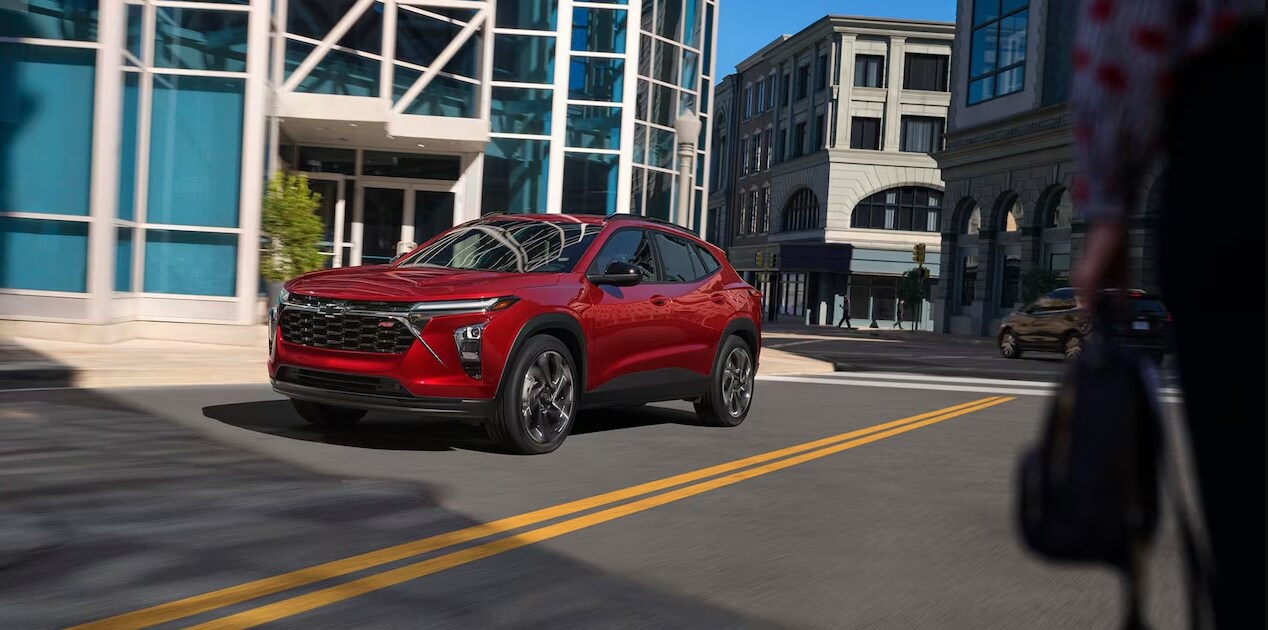 2023-chevy-trax-3.PNG A red 2023 Chevy Trax drives down a sunny street