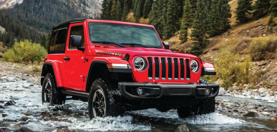 Dans Jeep Service Center A red Jeep Wrangler driving through a stream