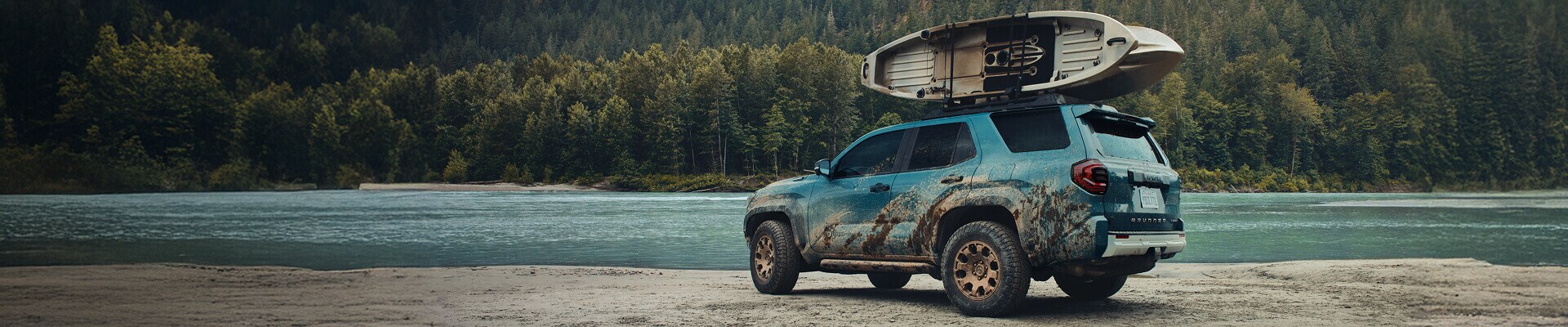 New 2025 Toyota 4Runner Hybrid Trailhunter in Everest parked aside a river with 2 kayaks in the roof rack