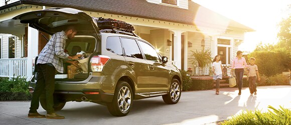 Father Packing the Trunk of a Green Subaru while Family Walks Toward Him
