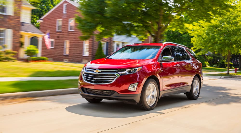 A red 2018 Chevy Equinox is shown driving on a suburban street after leaving a used Chevy …