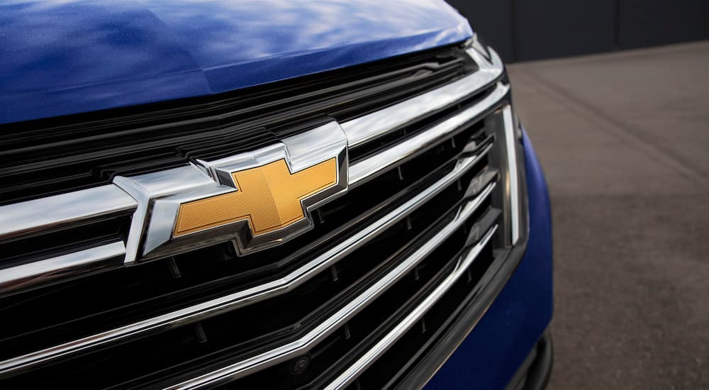 A close up shows the bowtie badge on the grille of a blue 2023 Chevy Equinox LT.