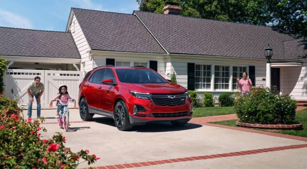 A red 2024 Chevy Equinox is shown parked in a driveway after visiting a Chevy dealer near Bexley.
