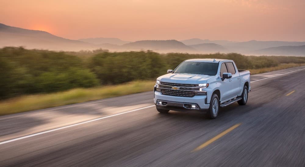 A white 2020 Chevy Silverado 1500 is shown driving on an open highway.