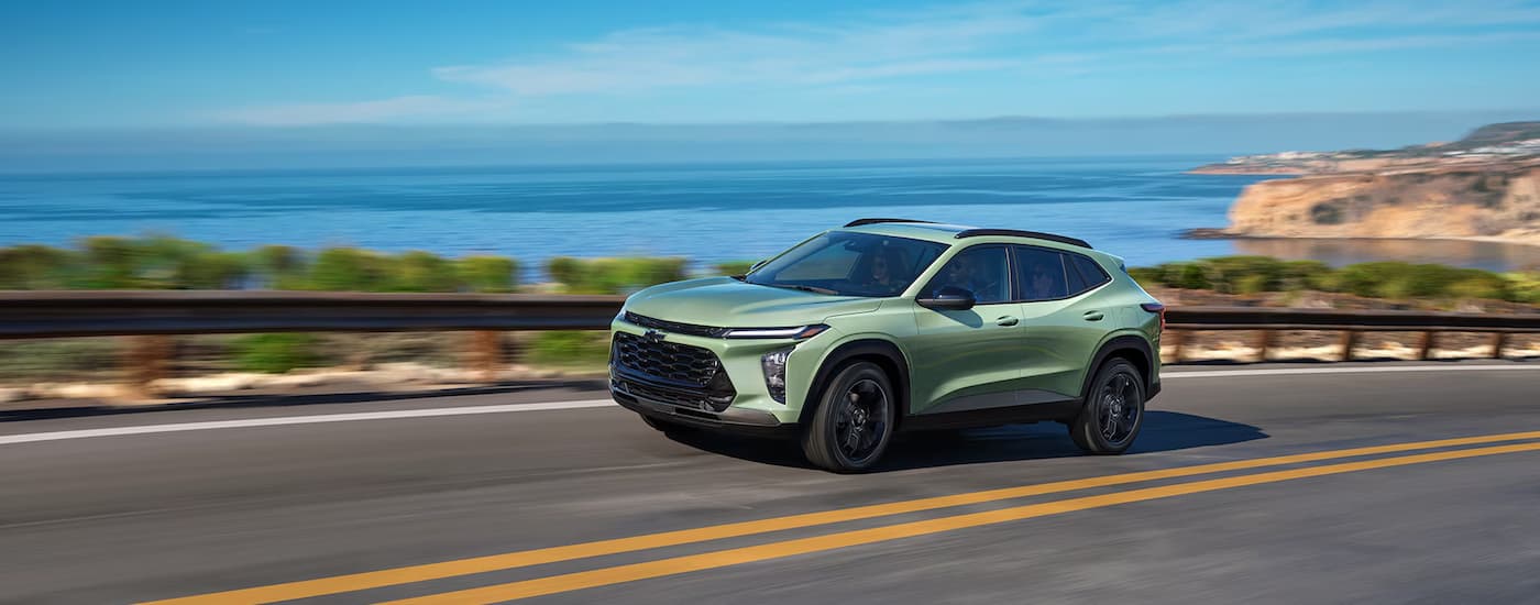 2025%20Chevy%20Trax%20-%20Green%20Highway.jpg A green 2025 Chevy Trax ACTIV is driving on a winding highway.