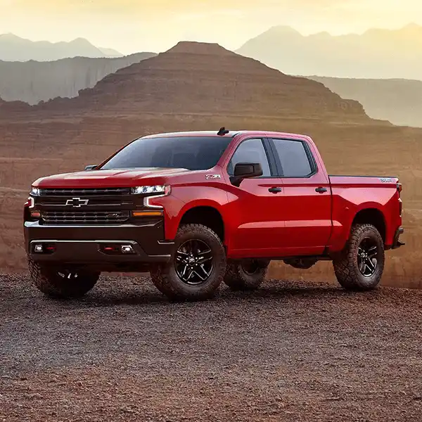 Red Chevrolet Silverado truck driving near the mountains