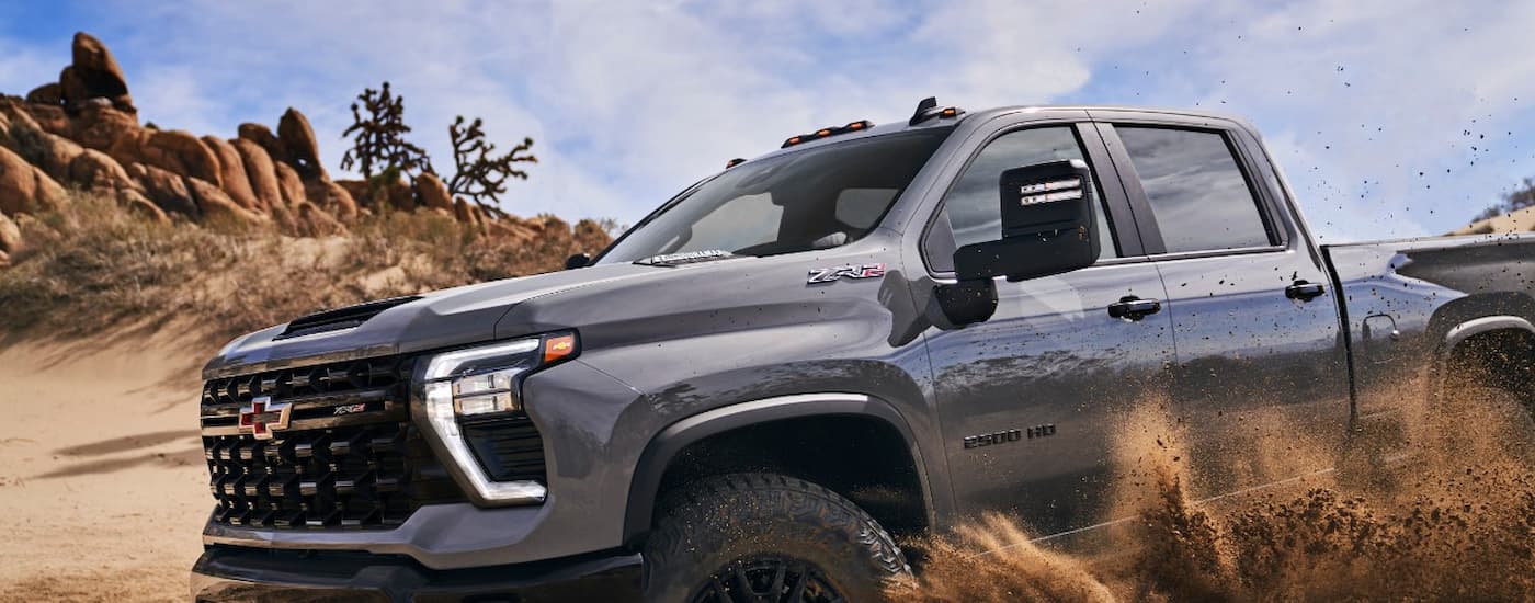 Chevy%20Silverado%201500%20for%20sale%20in%20Columbus%20-%202024%20Chevy%20Silverado%202500%20HD%20ZR2%20-%20Side%20Sand.jpg A close up of the front of a grey 2024 Chevy Silverado 2500HD ZR2 off-roading on a sandy area.