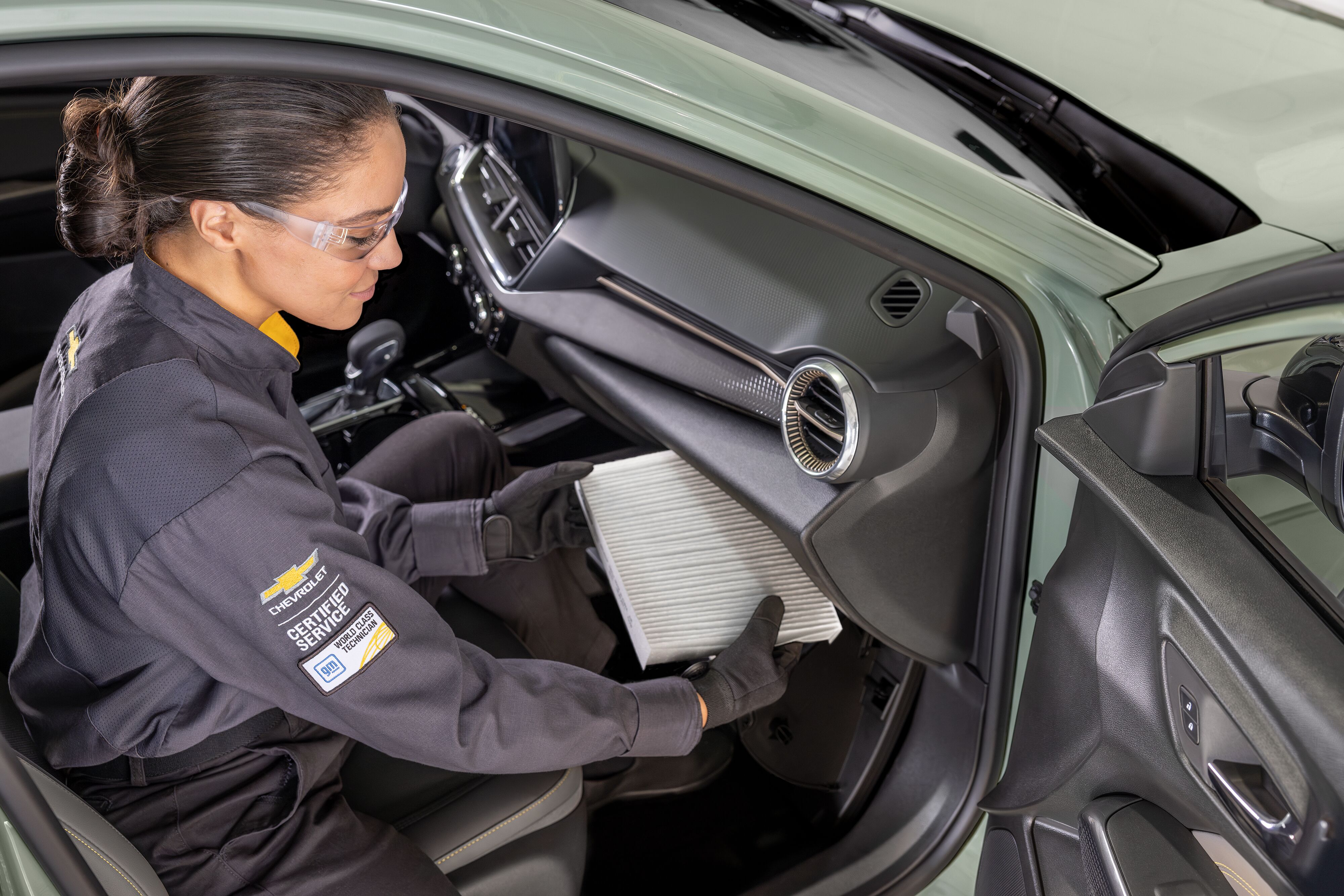 Chevy Maintenance Female Chevrolet certified service technician replacing cabin air filter behind the glove compartment.