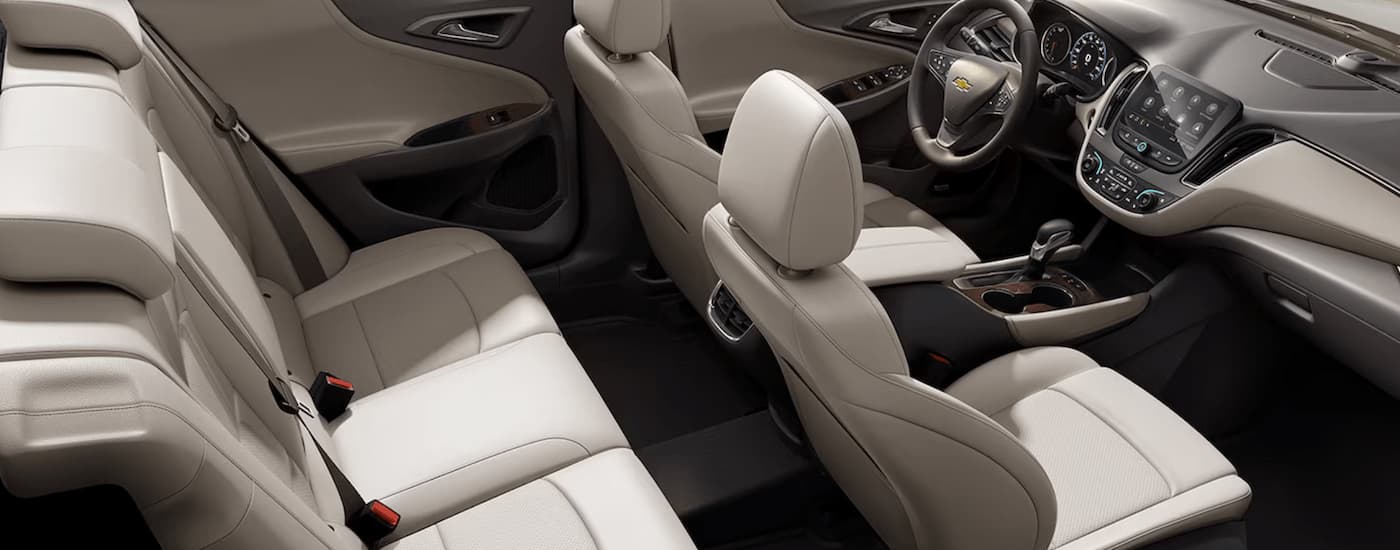 The tan interior of a 2024 Chevy Malibu shows the front seating and center console.
