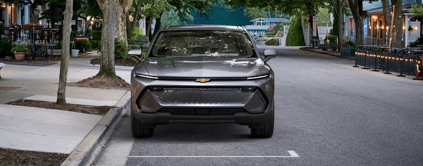 A grey 2024 Chevy Equinox EV 1LT is shown from the front parked on athe side of a city street.