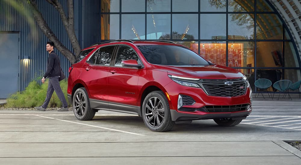 A red 2023 Chevy Equinox RS is shown parked in front of a building with lots of windows.