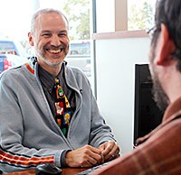 Car salesman smiling at desk
