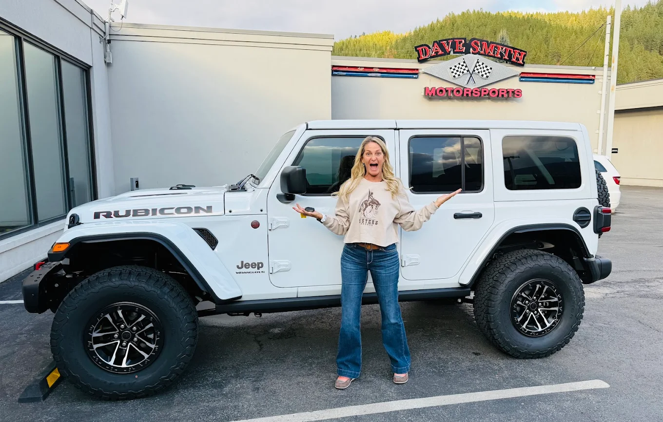 Woman smiling in front of her new Jeep Wrangler from Dave Smith Motors