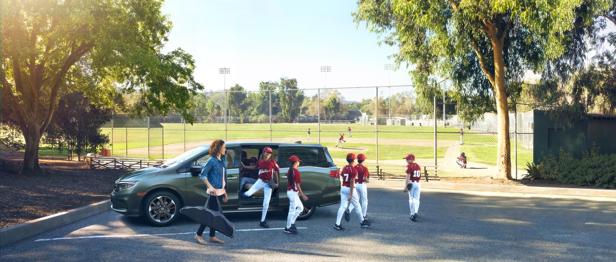 2024-Honda-Odyssey-Elite-Van-L04.png gray Honda Odyssey minivan parked at a baseball field