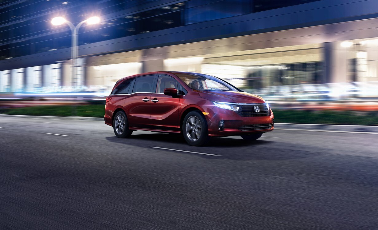 maroon Honda Odyssey minivan driving through a blurred city