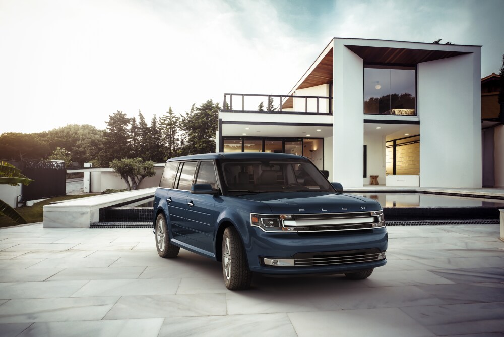 2018-Ford-Flex-Limited-SUV-L02 (1).png blue Ford Flex SUV parked in front of a modern home