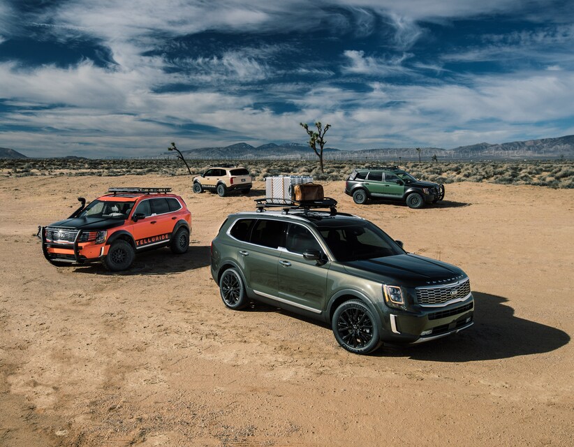 2020-KIA-Telluride-SX-SUV-S07.png 4 Kia Telluride SUV models parked in the desert, 2 green models, 1 orange, 1 tan