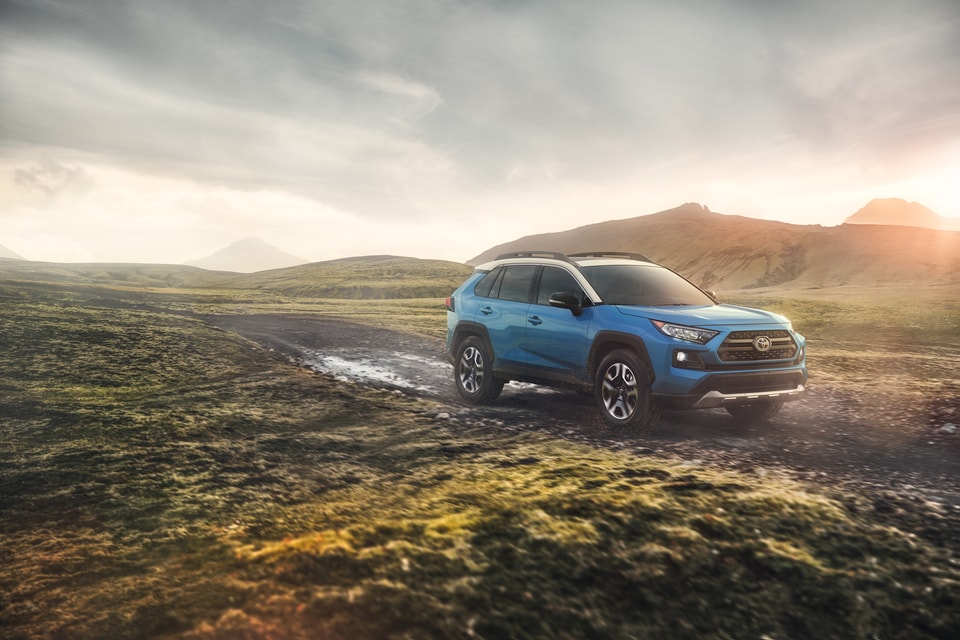 2019-Toyota-RAV4-Adventure-SUV-L01.png blue Toyota RAV4 SUV parked in a misty, mossy, rocky field