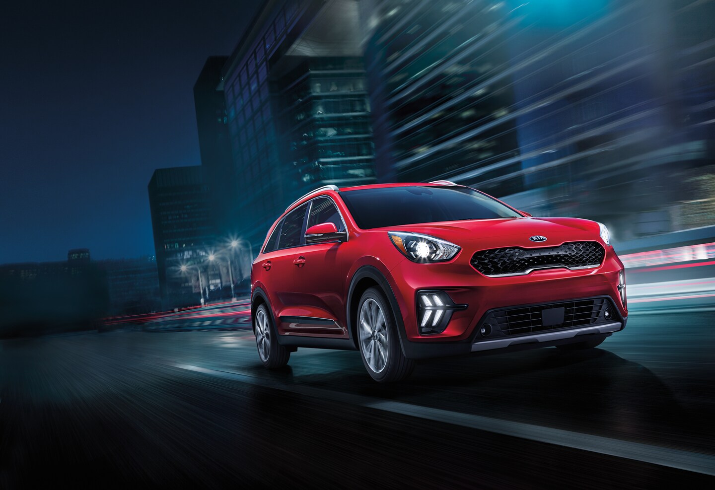 red Kia Niro SUV driving in a stylized city at a steep side angle