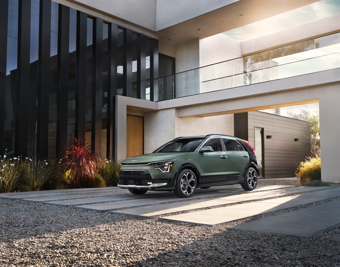 2023-KIA-NiroEV-Wave-SUV-L03.png dark green Kia Niro EV SUV parked in font of a modern home