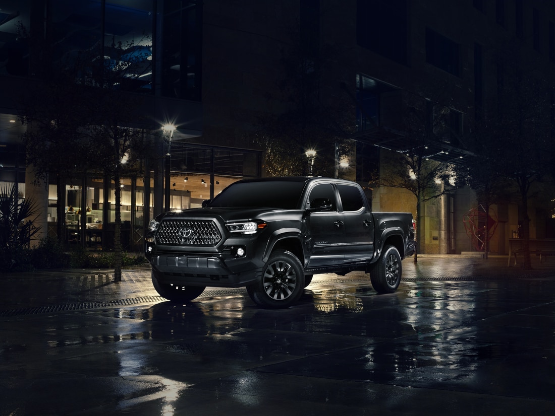 2022-Toyota-Tacoma-Limited-DoubleCab-NightshadeSpecialEdition-Truck-L01.png black Toyota Tacoma truck driving through downtown at night