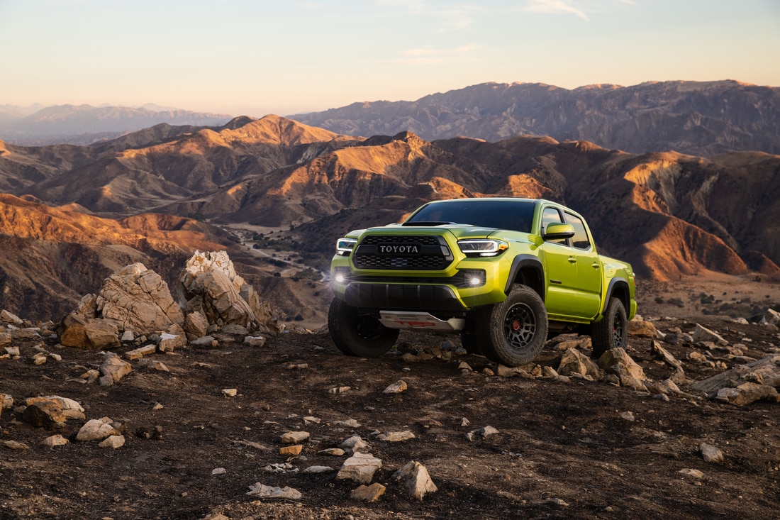 2023-Toyota-Tacoma-TRDPro-DoubleCab-Truck-L02.png yellow-green Toyota Tacoma truck parked at an angle on a rocky ridge