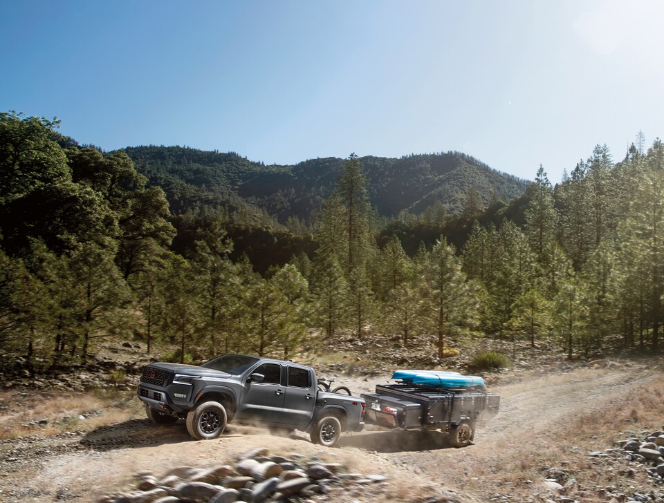 2022-Nissan-Frontier-PRO4X-CrewCab-Truck-L04.png silver Nissan Frontier truck driving through a dusty valley