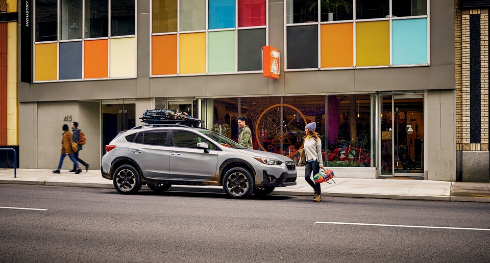2022-Subaru-Crosstrek-Premium-Hatchback-Crossover-SUV.png white Subaru Crosstrek crossover SUV parked in front of a colorful retail building