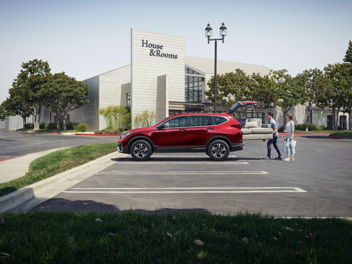 2021-Honda-CRV-LX-SUV-L02.png red Honda CR-V SUV parked in a furniture store lot with a couple putting a couch in the back
