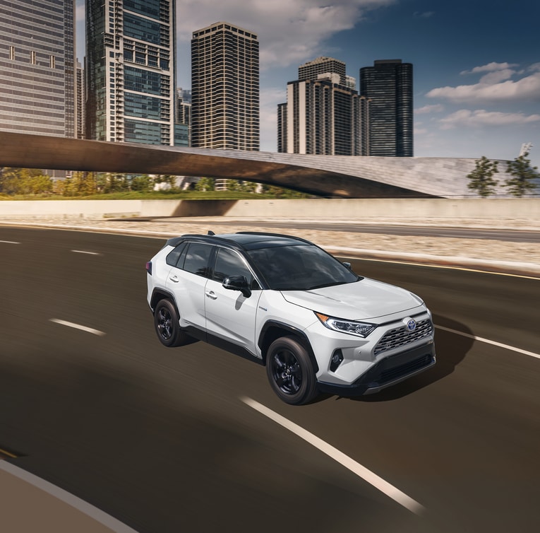 2021-Toyota-RAV4Hybrid-XSE-SUV-L01.png white Toyota RAV4 Hybrid SUV driving on the freeway