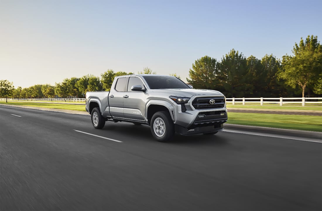 2024-Tacoma-SR5-DoubleCab-Truck-L03.png silver Toyota Tacoma truck driving near green grass