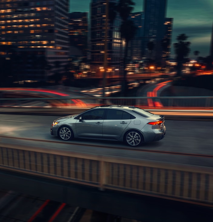 2021-Toyota-Corolla-XSE-Sedan.png grey Toyota Corolla sedan driving through a city at night